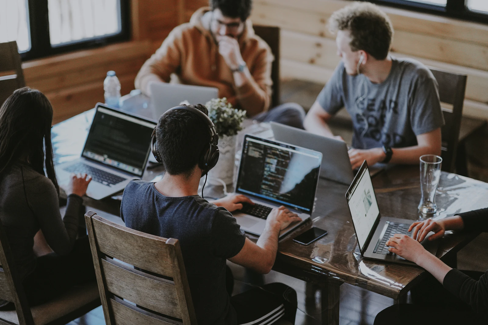 A small startup team working together on laptops around a wooden table